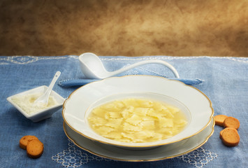 broth with ravioli over blue linen tablecloth