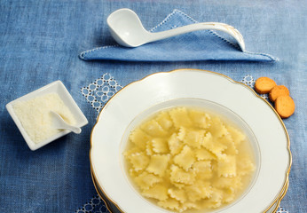 broth with ravioli over blue linen tablecloth
