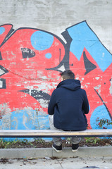 Young man seen from the back looking at a graffiti