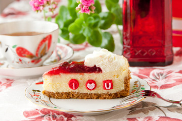 Piece of strawberry cheesecake with edible letters for Valentine