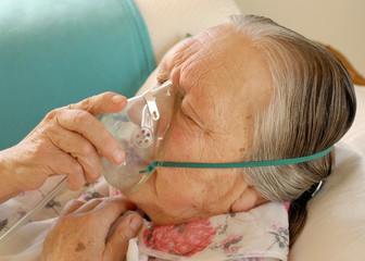 Seniorin atmet Sauerstoff ein durch eine Maske