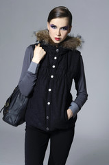 Fashion stylish girl with bag posing on gray background