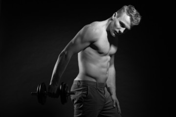 Obraz na płótnie Canvas Muscled fitness man holding dumbell. Black and white shot.