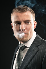 Obraz premium Fashion man in suit smoking cigarette. Studio shot.