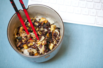 Wild rice dish with squid as snack at a workplace, chopsticks