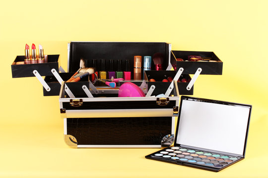 open case with cosmetics on yellow background