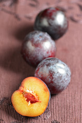 4 plums on table cloth close up