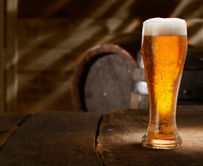 Glass of foamy beer on a table in a beer cellar