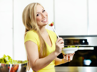 Pretty girl in the kitchen eating healthy food to lose weight