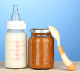 Baby food, bottle of milk and puree on blue background