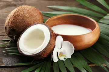 Coconut with leaves and flower, on grey wooden background
