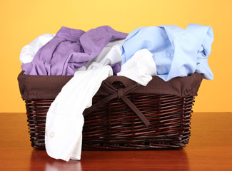 Bright clothes in laundry basket,on color background