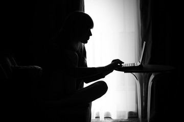 Woman working on laptop / Silhouette of young woman