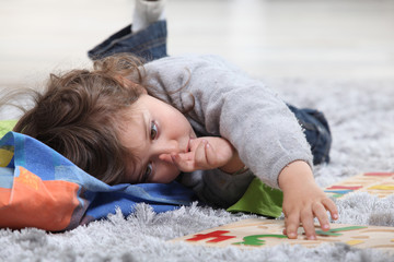 Child lying on the floor playing with a puzzle