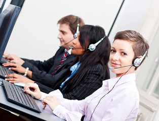 Callcenter Mitarbeiter mit Kopfhörern am Computer freundlich