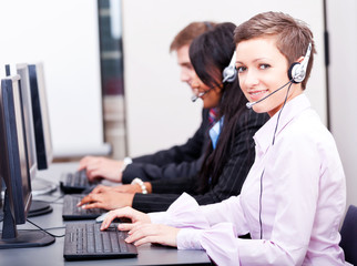 Callcenter Mitarbeiter mit Kopfhörern am Computer freundlich