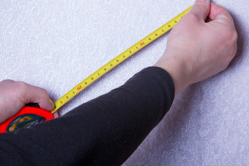 man's hand holding a tape measure