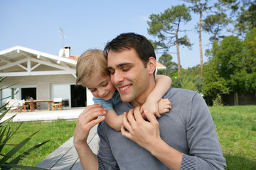 Father giving kid piggy-back in the garden