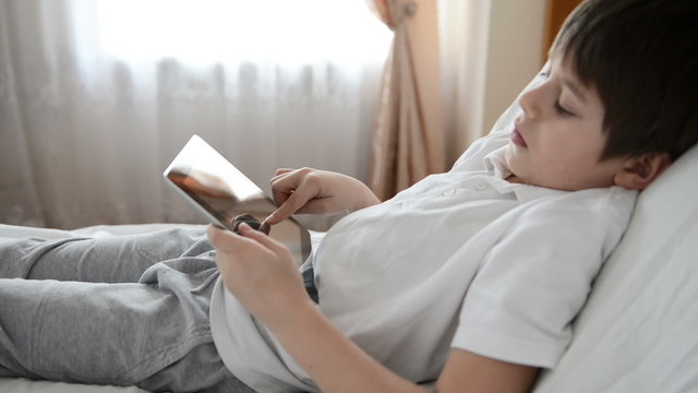child uses tablet pc lying on a sofa