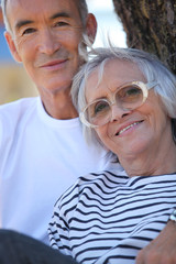 Elderly couple stood by tree in park