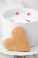 cup of hot milk with foam, decorated with sugar hearts and heart