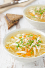 two bowls of vegetable soup with chicken and parsley closeup