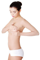 Woman examining breast mastopathy or cancer.