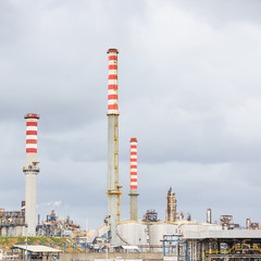 Oil refinery industry, smoke stacks on cloudy sky background