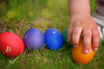 Fototapeta na wymiar Ręka dziecko biorąc zdobione Easter egg z trawy