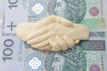 Uścisk dłoni nad banknotami PLN