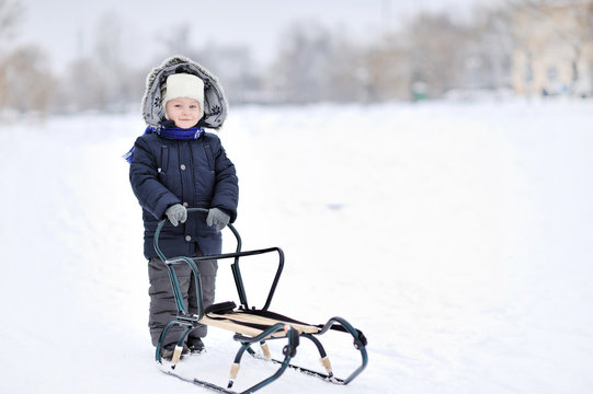 Little boy with sled in winter