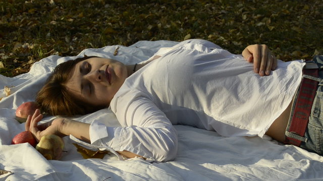 Young woman lying on bedspread in autumn park