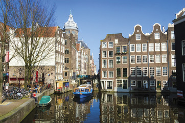 Obraz premium Niebieska łódź na kanale w Amsterdamie. Typowy architekt Amsterdamu