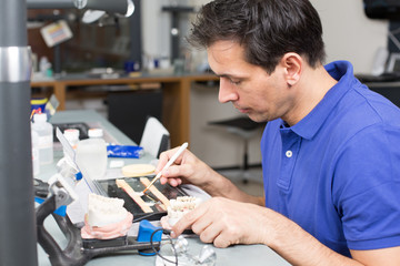 Dental lab technician appying porcelain to mold