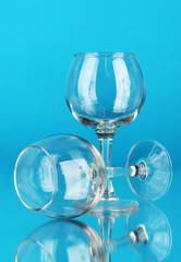 Two empty wine glasses on color background