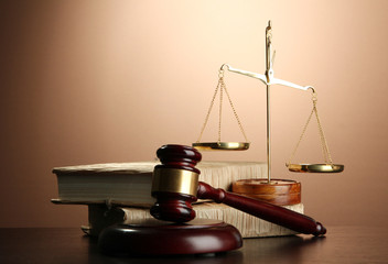 Golden scales of justice, gavel and books on brown background