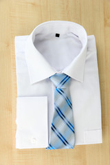 New white man's shirt with color tie on wooden background