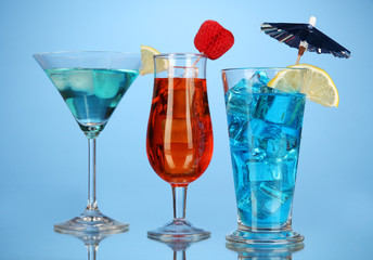Alcoholic cocktails with ice on blue background