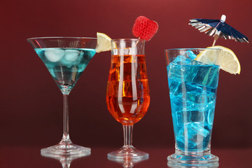 Alcoholic cocktails with ice on darck red background