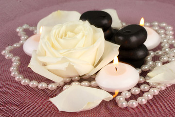 Obraz na płótnie Canvas kamienie spa z kwiatów i świec w wodzie na talerzu