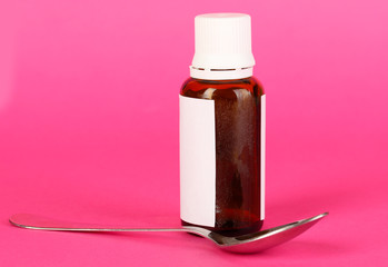 Medical drops and spoon for them on pink background