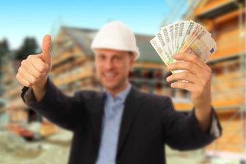 Architekt mit Geldscheinen in der Hand vor Baustelle