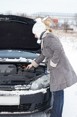 Car break - woman looks into the engine compartment