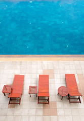 top view of poolside deckchairs alongside blue swimming pool