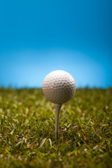 Golf ball on green grass over a blue background 