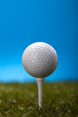 Golf ball on green grass over a blue background 
