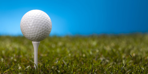Golf ball on green grass over a blue background 