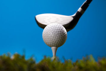 Golf ball on green grass over a blue background 