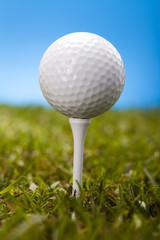 Golf ball on green grass over a blue background 