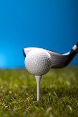 Golf ball on green grass over a blue background 